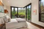 Experience luxurious mountain living in this stunning bedroom featuring a king-sized bed with plush white linens and a cozy throw blanket.