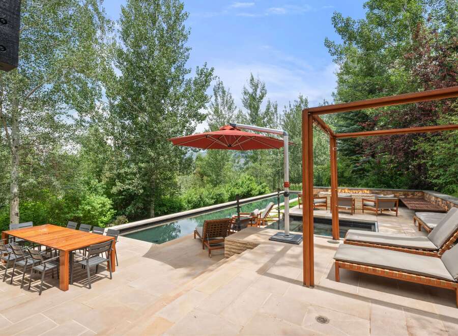 Experience luxury outdoor living with this stunning patio featuring a sleek infinity pool and a cozy fire pit area.