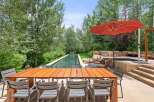 This stunning outdoor living space features a rectangular swimming pool surrounded by lush greenery and a spacious patio.
