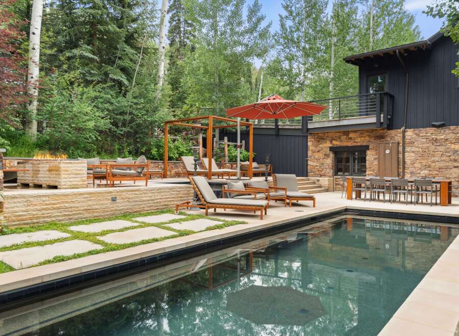 Experience luxury outdoor living with this stunning backyard oasis, featuring a sparkling swimming pool and a modern fire pit area perfect for evening gatherings.