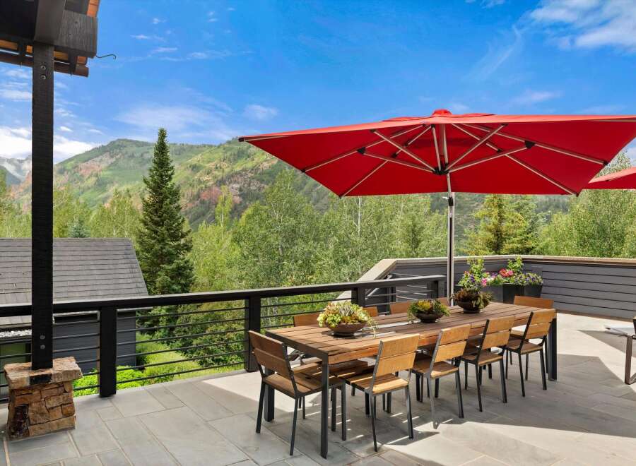 Enjoy breathtaking mountain views from this stunning outdoor dining area, complete with a large wooden table and chairs perfect for al fresco meals.