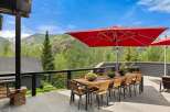 Enjoy breathtaking mountain views from this stunning outdoor dining area, complete with a large wooden table and chairs perfect for al fresco meals.