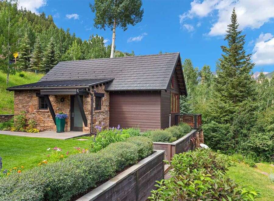 Nestled amidst lush greenery and mature trees, this charming stone and wood cabin offers a serene mountain retreat.