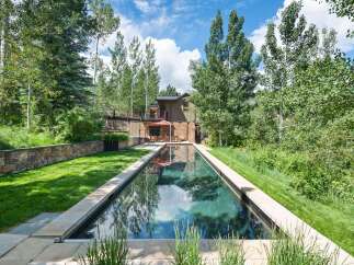 Experience luxury outdoor living with this stunning rectangular swimming pool, perfectly integrated into a lush, green landscape.