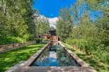 Experience luxury living with this stunning property featuring a sleek, rectangular swimming pool that reflects the vibrant blue sky and lush greenery.