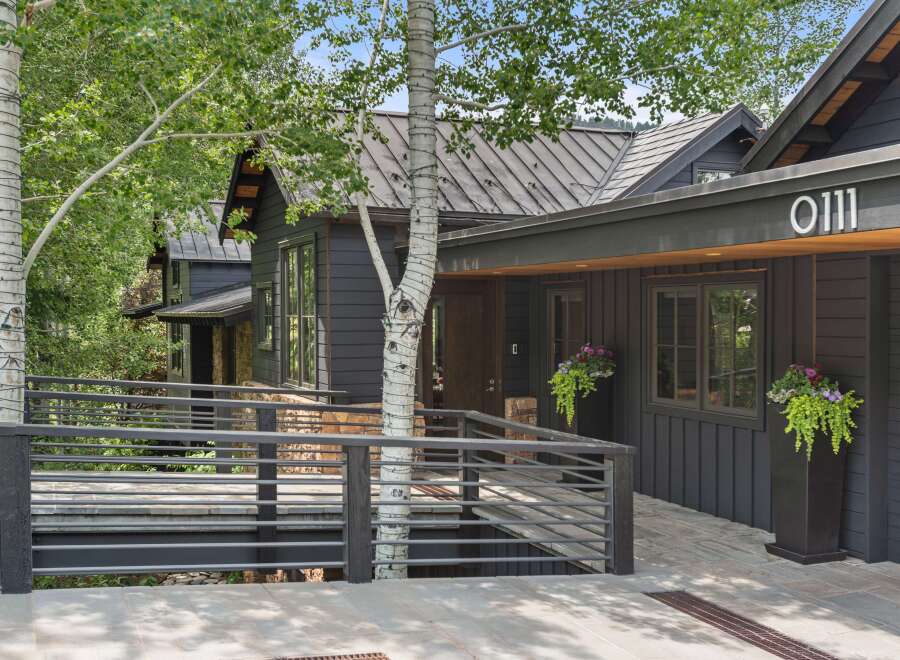 Experience modern mountain living in this stunning dark-clad home, featuring a sleek metal roof and a welcoming ramp leading to the entrance.