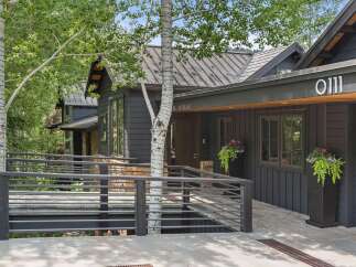Experience modern mountain living in this stunning dark-clad home, featuring a sleek metal roof and a welcoming ramp leading to the entrance.