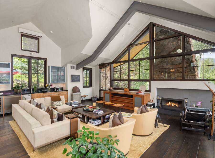 Experience luxury mountain living in this stunning great room, featuring a soaring vaulted ceiling with exposed beams and a dramatic floor-to-ceiling stone fireplace.