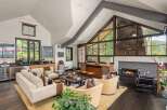 Experience luxury mountain living in this stunning great room, featuring a soaring vaulted ceiling with exposed beams and a dramatic floor-to-ceiling stone fireplace.