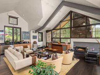 Experience luxury mountain living in this stunning great room, featuring a soaring vaulted ceiling with exposed beams and a dramatic floor-to-ceiling stone fireplace.