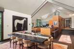 This spacious dining and kitchen area features a large, dark wood dining table set for a gathering, complemented by a striking black and white horse painting.