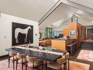 This spacious dining and kitchen area features a large, dark wood dining table set for a gathering, complemented by a striking black and white horse painting.