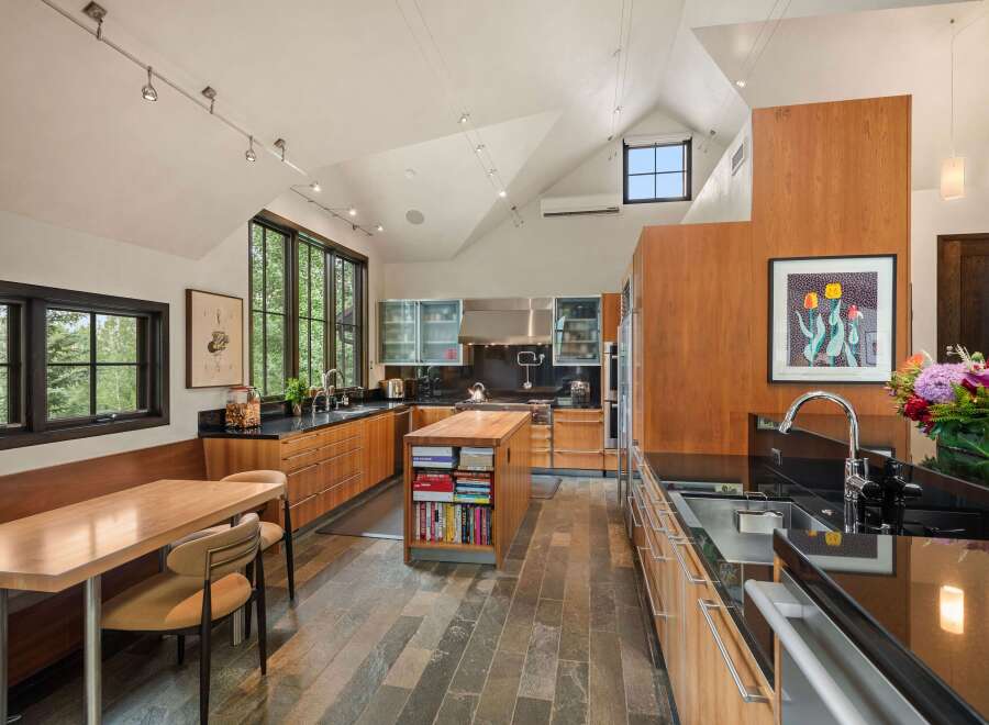 Experience culinary excellence in this stunning modern kitchen, featuring sleek cherry wood cabinetry and expansive black granite countertops.
