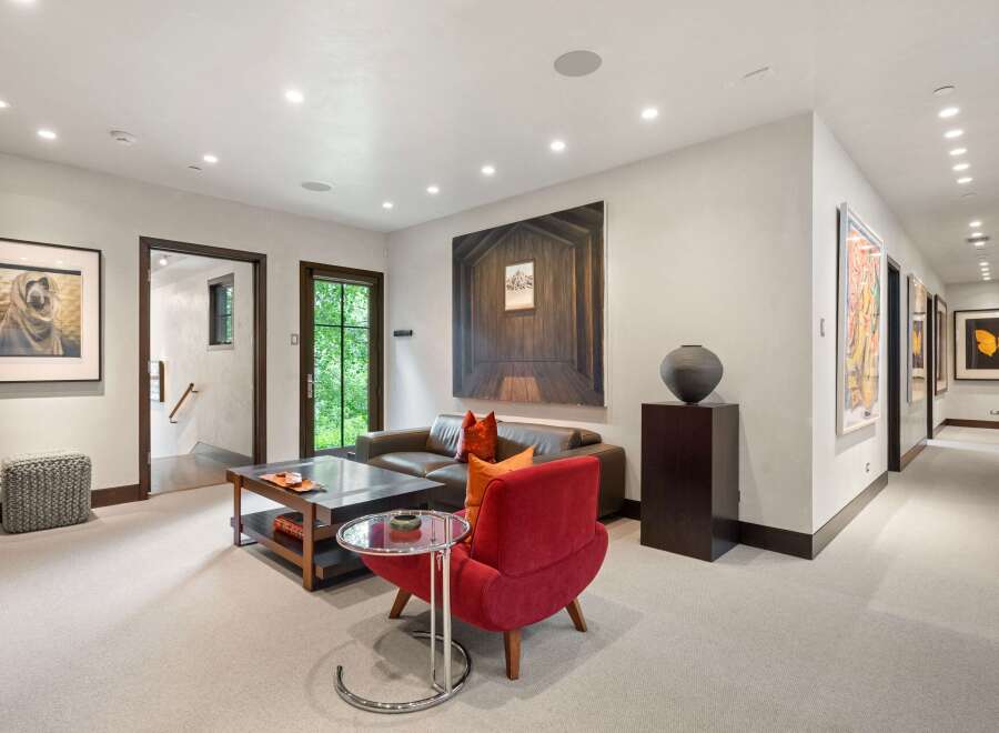 Experience sophisticated living in this inviting lounge area, featuring a plush red armchair and a sleek leather sofa perfect for relaxation.