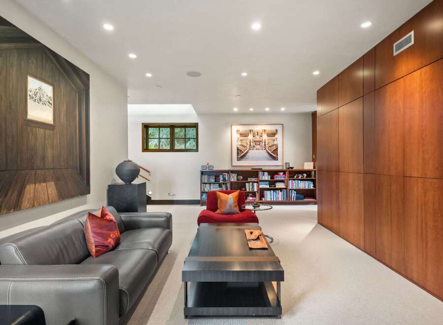 This spacious living area features a sleek dark leather sofa complemented by a vibrant red accent chair, perfect for relaxation.