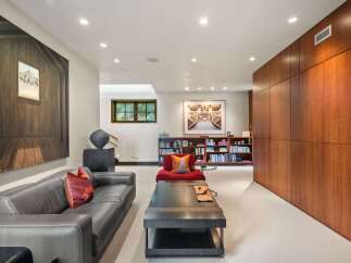 This spacious living area features a sleek dark leather sofa complemented by a vibrant red accent chair, perfect for relaxation.