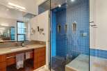 Experience modern luxury in this stunning bathroom featuring a spacious walk-in shower with vibrant blue tilework and multiple shower heads.