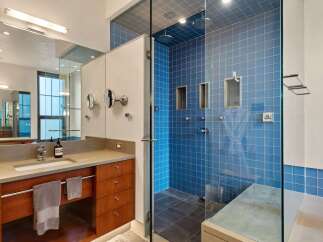 Experience modern luxury in this stunning bathroom featuring a spacious walk-in shower with vibrant blue tilework and multiple shower heads.