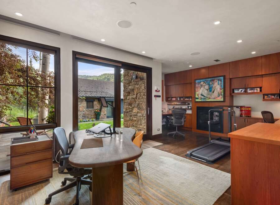 This home office offers a productive and inspiring workspace with large windows overlooking a serene natural landscape.