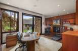 This home office offers a productive and inspiring workspace with large windows overlooking a serene natural landscape.