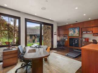 This home office offers a productive and inspiring workspace with large windows overlooking a serene natural landscape.