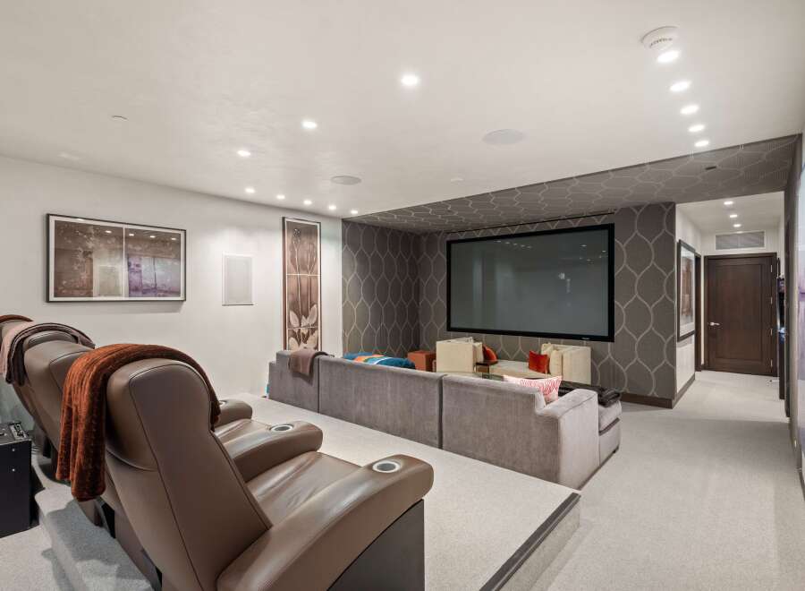 Experience ultimate entertainment in this luxurious home theater, featuring plush reclining seats with cup holders and a massive projector screen.