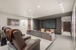 Experience ultimate entertainment in this luxurious home theater, featuring plush reclining seats with cup holders and a massive projector screen.