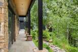 Experience luxurious mountain living with this stunning property featuring a covered stone patio and expansive windows.