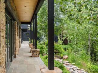 Experience luxurious mountain living with this stunning property featuring a covered stone patio and expansive windows.