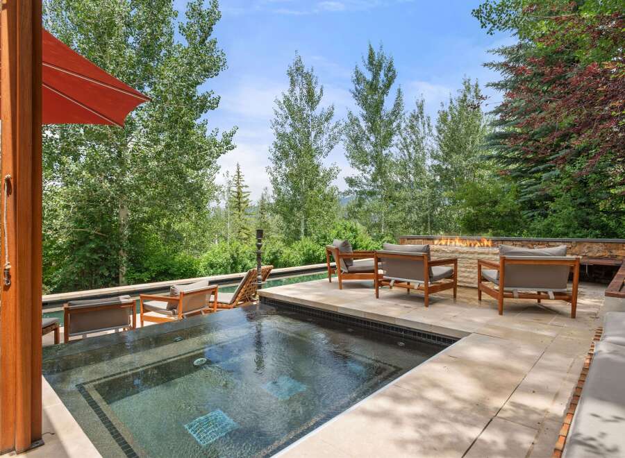 Experience luxury outdoor living with this stunning patio featuring a modern hot tub and a sleek gas fireplace.