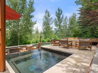 Experience luxury outdoor living with this stunning patio featuring a modern hot tub and a sleek gas fireplace.