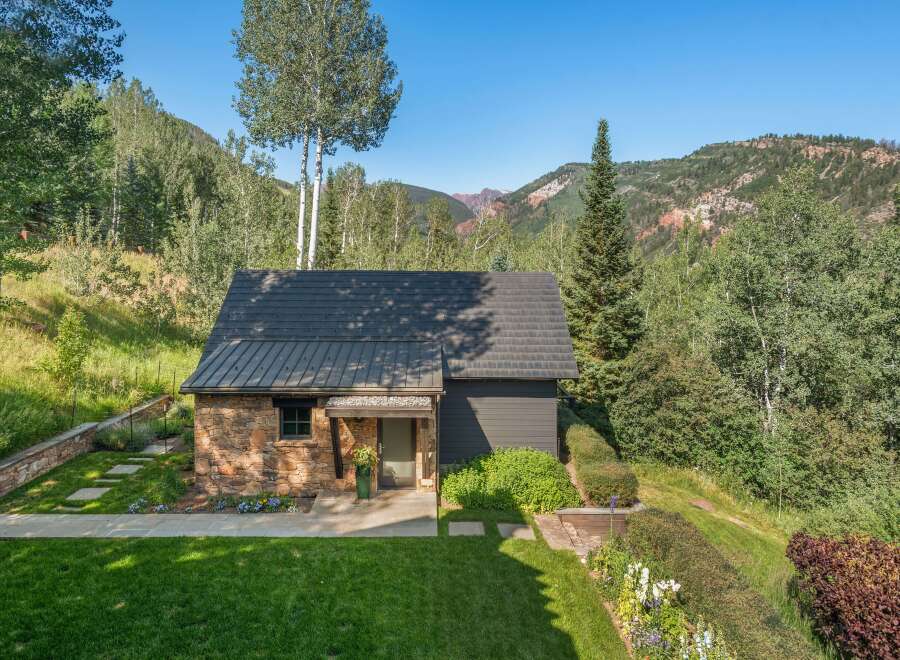 Nestled amidst a lush forest and majestic mountains, this charming stone and dark wood home offers a serene retreat.