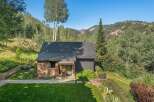 Nestled amidst a lush forest and majestic mountains, this charming stone and dark wood home offers a serene retreat.