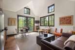 This spacious studio apartment offers a bright and airy living space with large windows framing lush forest views.