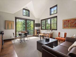 This spacious studio apartment offers a bright and airy living space with large windows framing lush forest views.