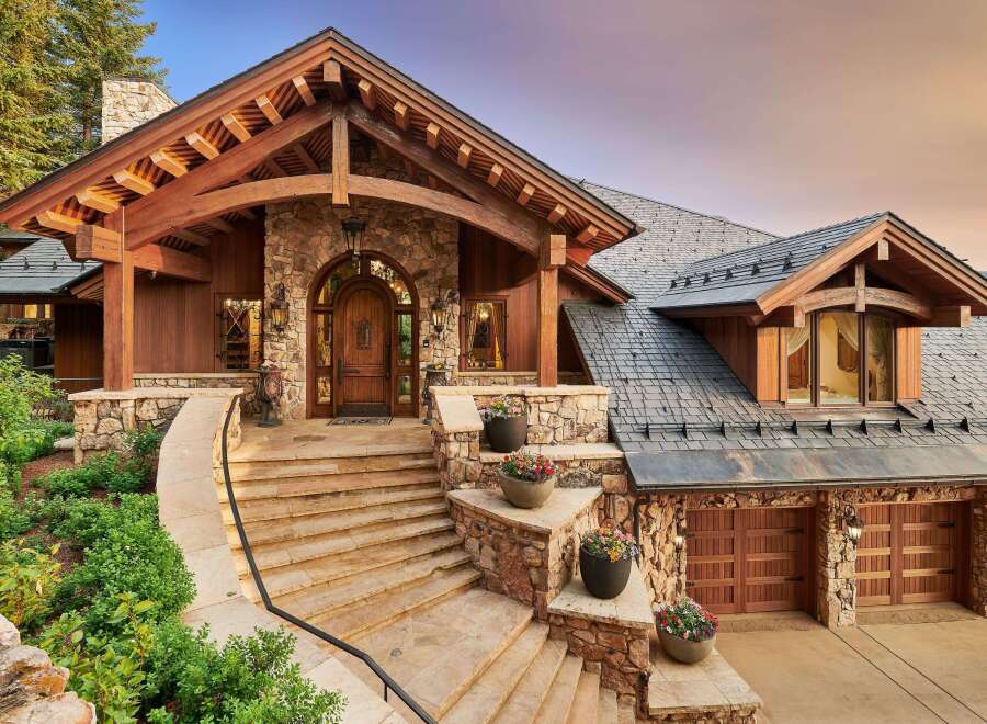 Experience luxury mountain living in this stunning custom-built home, featuring a grand stone and timber entrance with a majestic arched wooden door.