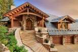 Experience luxury mountain living in this stunning custom-built home, featuring a grand stone and timber entrance with a majestic arched wooden door.