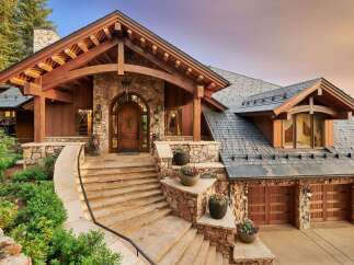 Experience luxury mountain living in this stunning custom-built home, featuring a grand stone and timber entrance with a majestic arched wooden door.