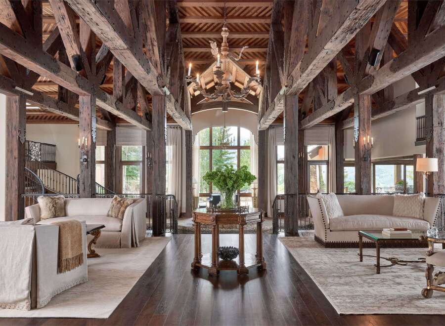 Experience rustic luxury in this grand living space, featuring soaring exposed wooden beams and a magnificent chandelier.