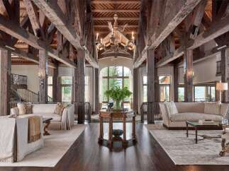 Experience rustic luxury in this grand living space, featuring soaring exposed wooden beams and a magnificent chandelier.