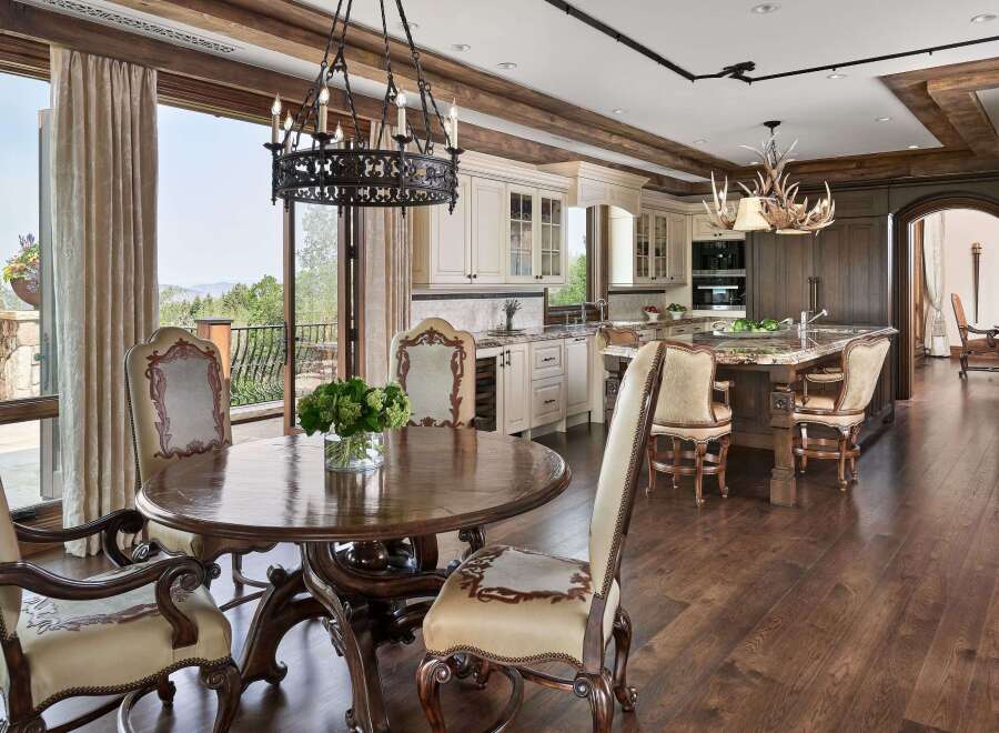 Experience luxurious mountain living in this stunning kitchen and dining area, featuring a grand round dining table and elegant seating.