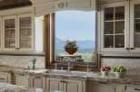 Experience breathtaking mountain views from this stunning kitchen, featuring elegant cream cabinetry and a large window overlooking a picturesque landscape.
