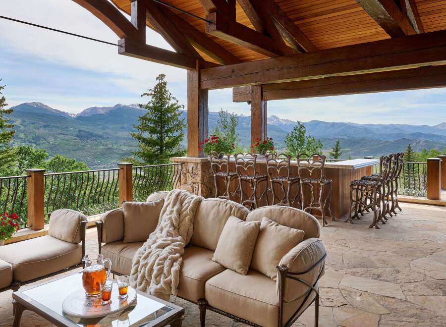 Experience luxury outdoor living with this stunning covered patio, featuring a full-service bar with ample seating and breathtaking mountain views.