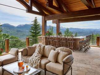 Experience luxury outdoor living with this stunning covered patio, featuring a full-service bar with ample seating and breathtaking mountain views.