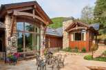 Experience luxury mountain living with this stunning property featuring a rustic stone and wood exterior, expansive windows, and a beautiful stone patio.