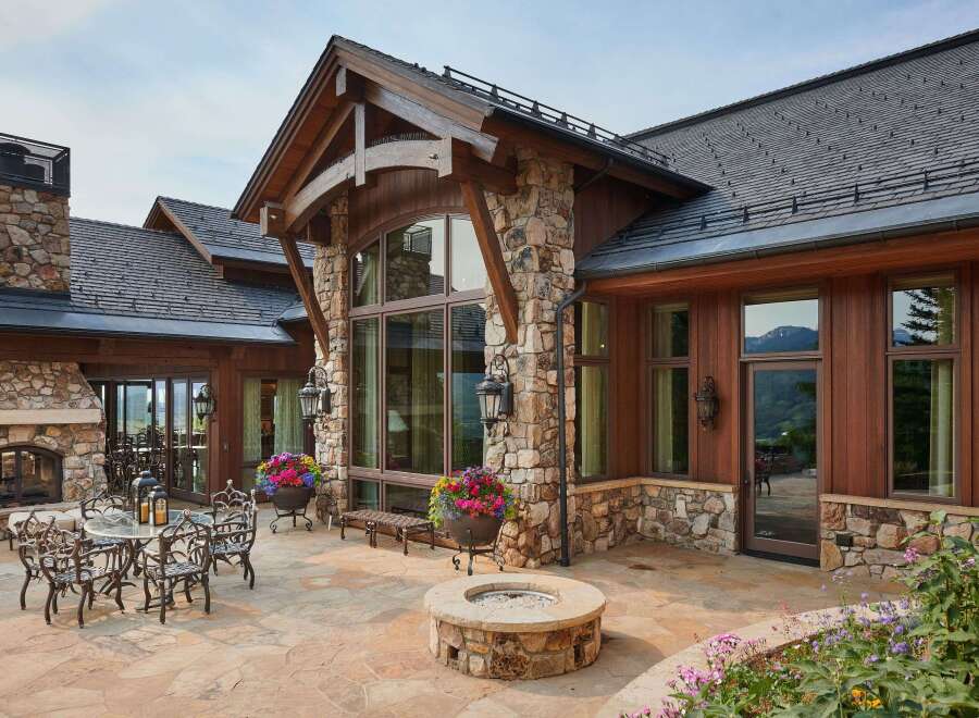 Experience luxury mountain living with this stunning stone and wood home, featuring a spacious stone patio perfect for entertaining.