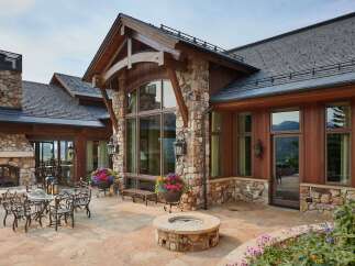 Experience luxury mountain living with this stunning stone and wood home, featuring a spacious stone patio perfect for entertaining.