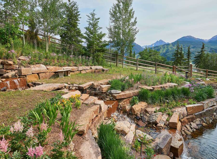 Discover this stunning mountain retreat featuring a beautifully landscaped garden with a cascading water feature and a tranquil pond.