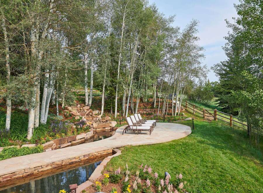 Escape to this serene mountain retreat featuring a tranquil water feature and a stone patio perfect for outdoor relaxation.