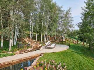 Escape to this serene mountain retreat featuring a tranquil water feature and a stone patio perfect for outdoor relaxation.